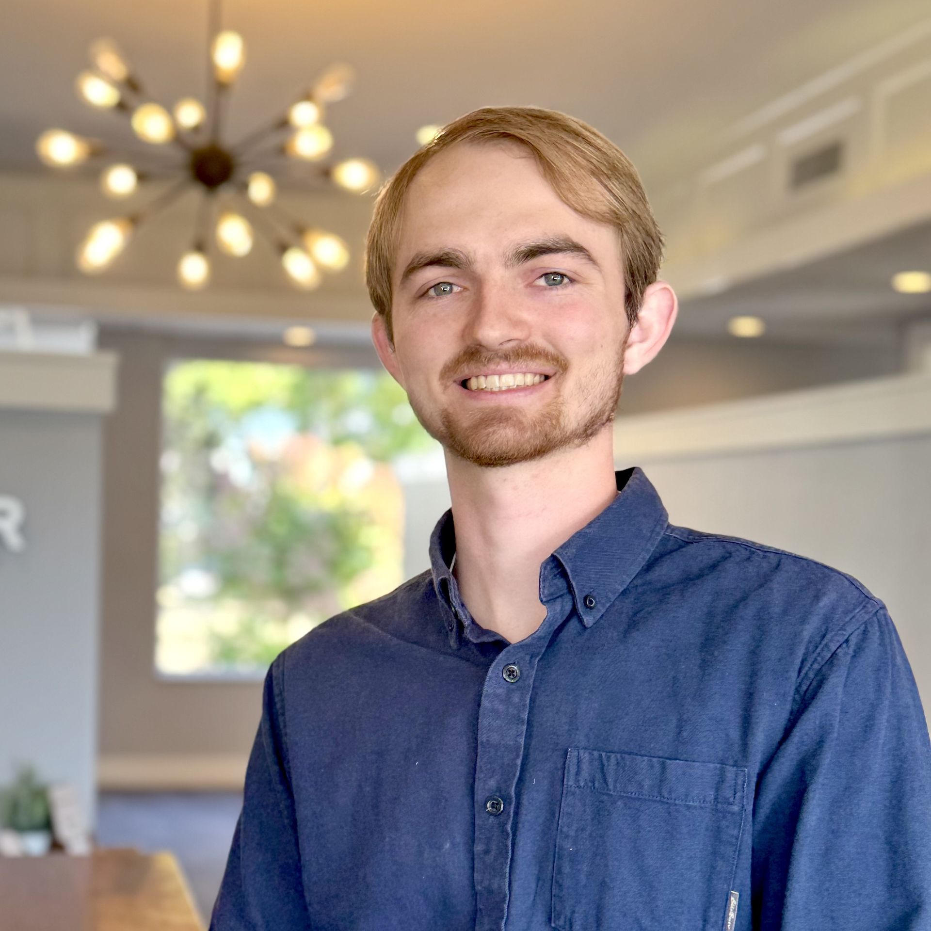 A woman wearing glasses and a red top is smiling for the camera.