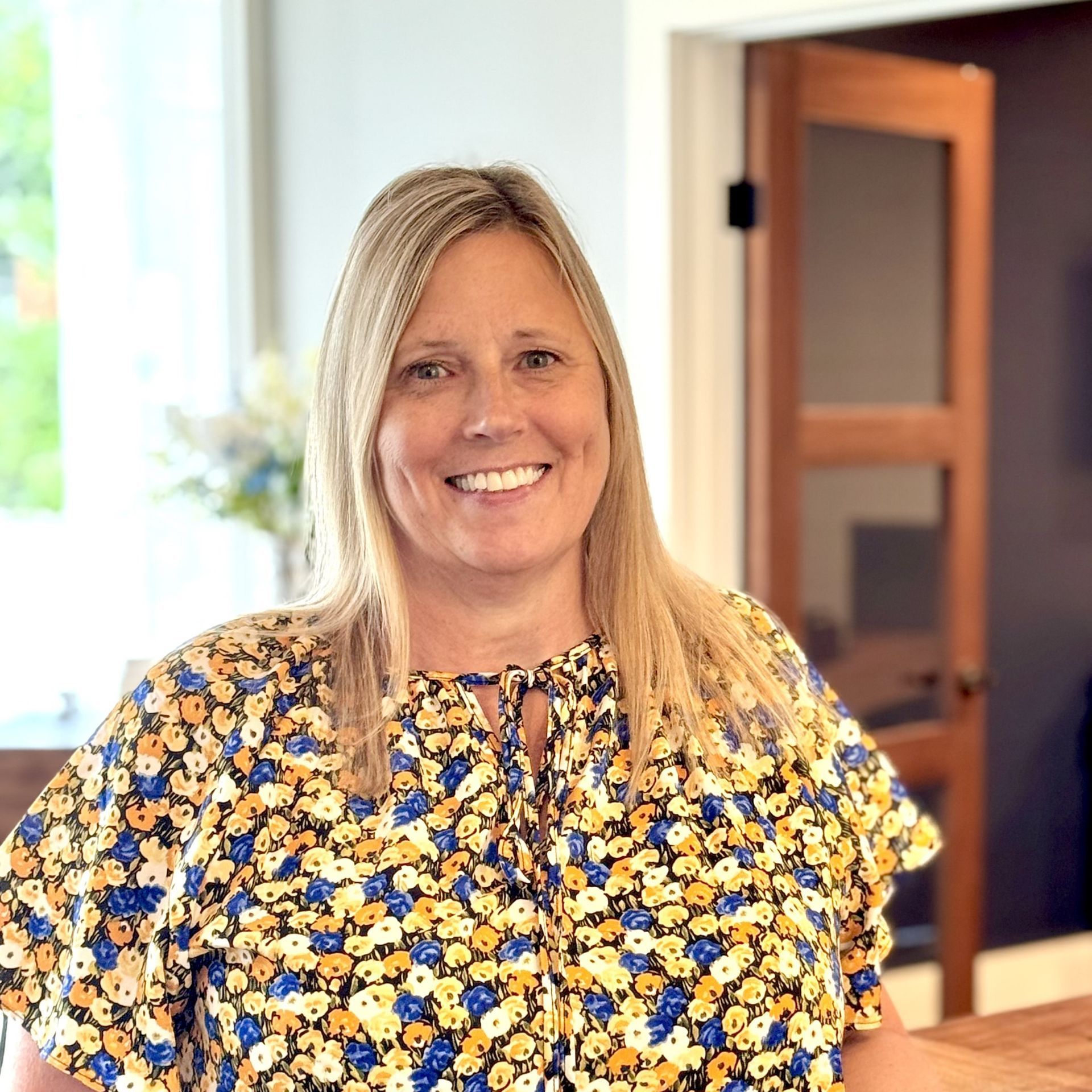 A woman wearing floral top is smiling for the camera.