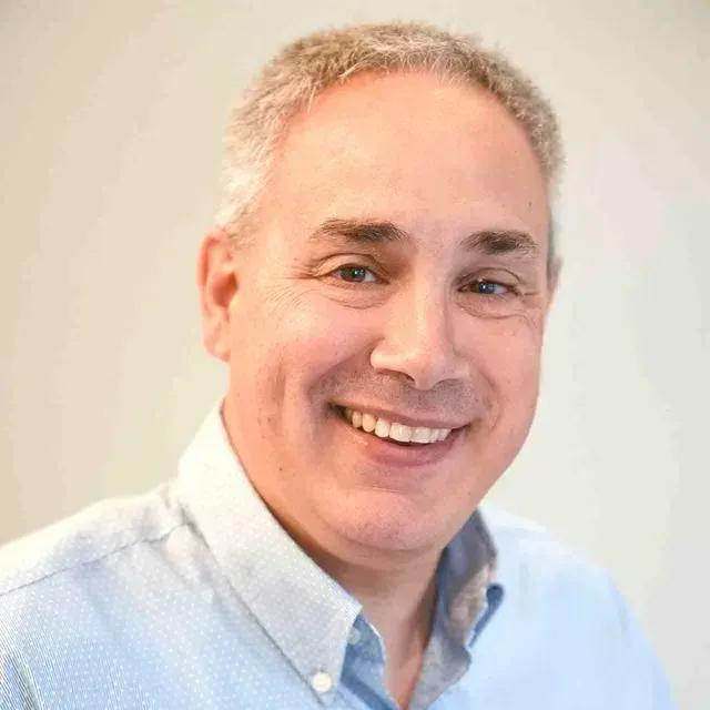 A gentleman with light hair and light blue shirt smiling