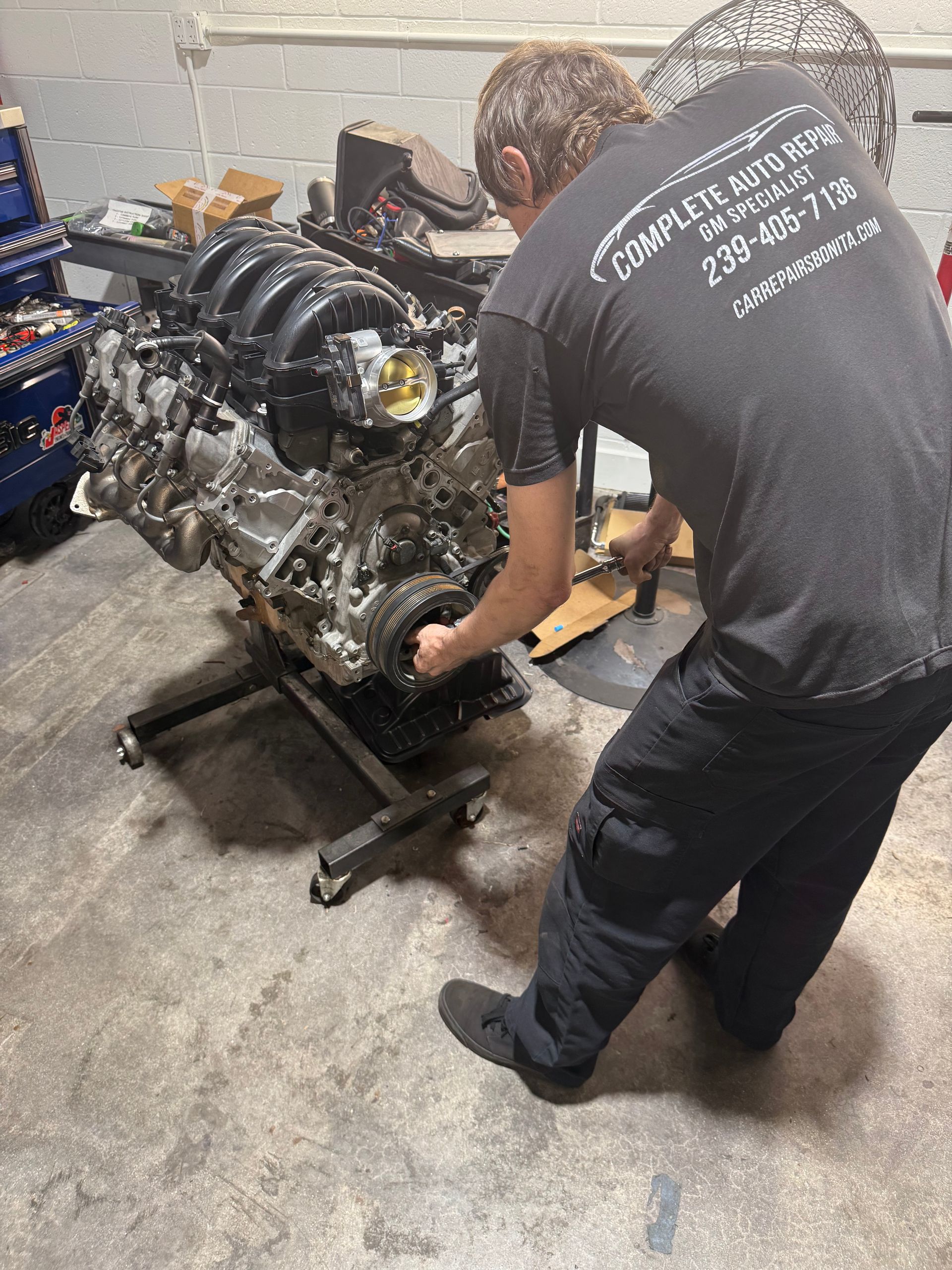 Mechanic adjusting a large engine on a stand in a workshop.
