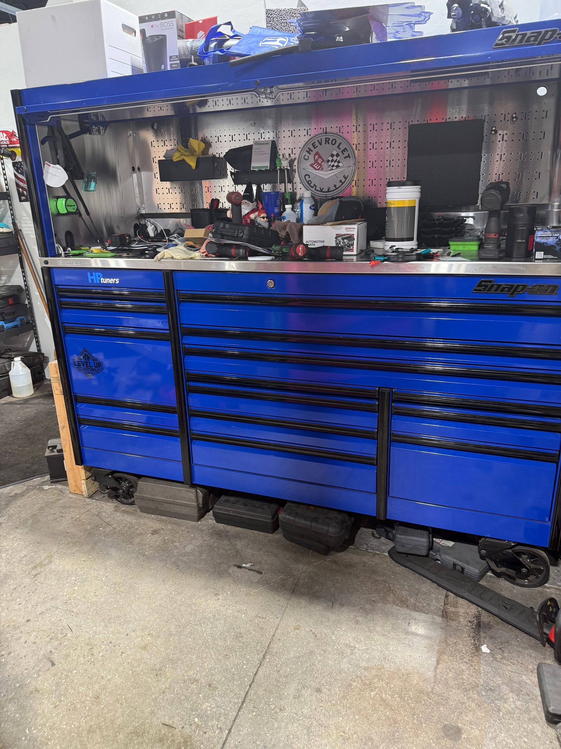 Blue tool chest and workbench in a garage workshop, with tools and supplies on the wall.