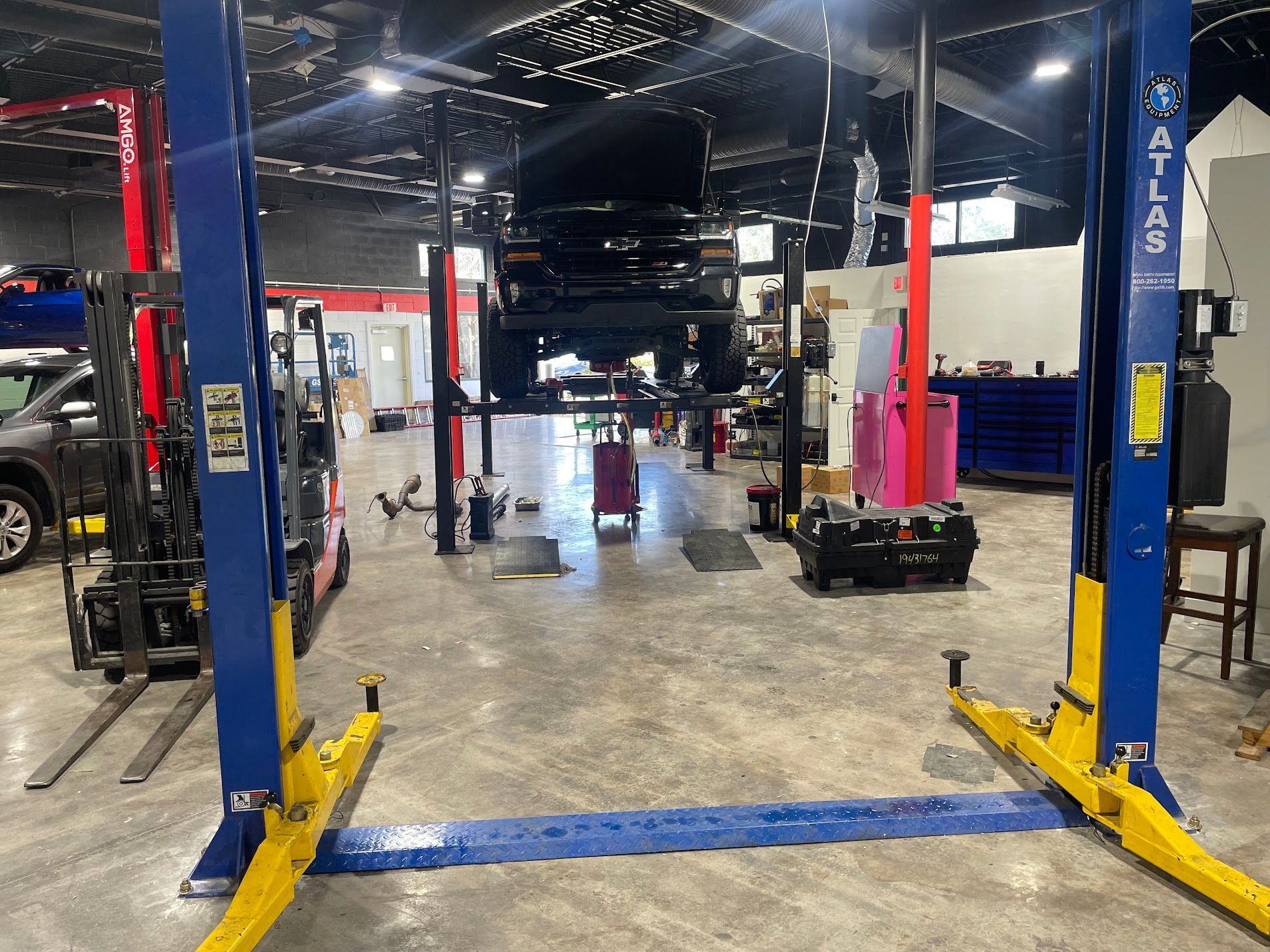 Auto repair shop with blue car lifts and vehicles in a service bay.