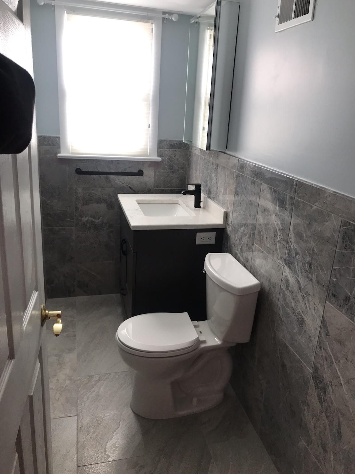 A bathroom with a toilet , sink and mirror