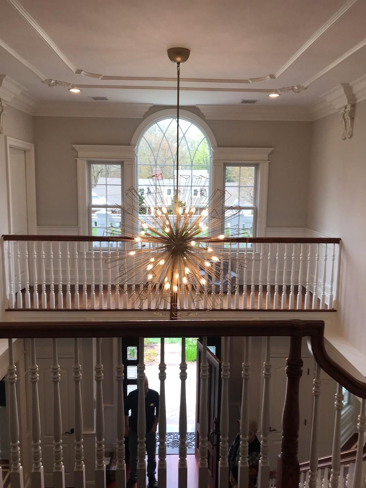 A large chandelier is hanging from the ceiling of a house.