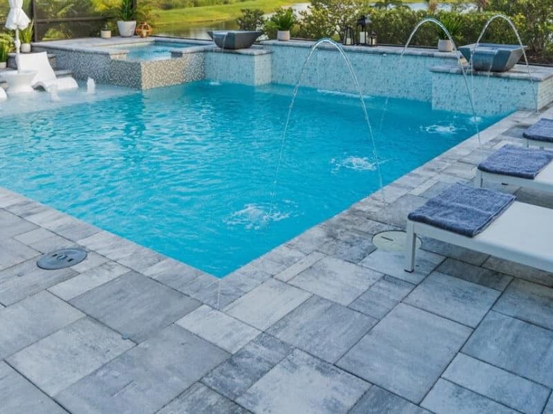 Outdoor swimming pool with blue water, stone deck, and white lounge chairs