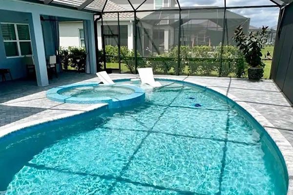 Screened backyard pool with a hot tub, white lounge chairs, and a turquoise water view