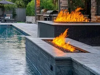 Modern pool patio with two rectangular fire pits burning beside the water