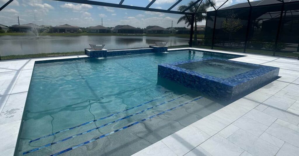 Modern backyard swimming pool with a blue-tiled ledge and a view of water and mountains beyond