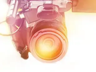 Close-up of a DSLR camera lens glowing with warm light, mounted on a stabilizer