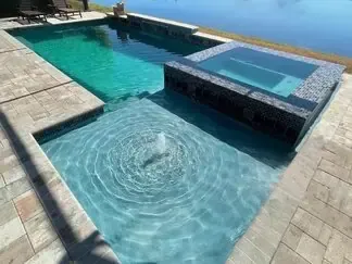 Modern backyard pool with a shallow spa and sunlit turquoise water