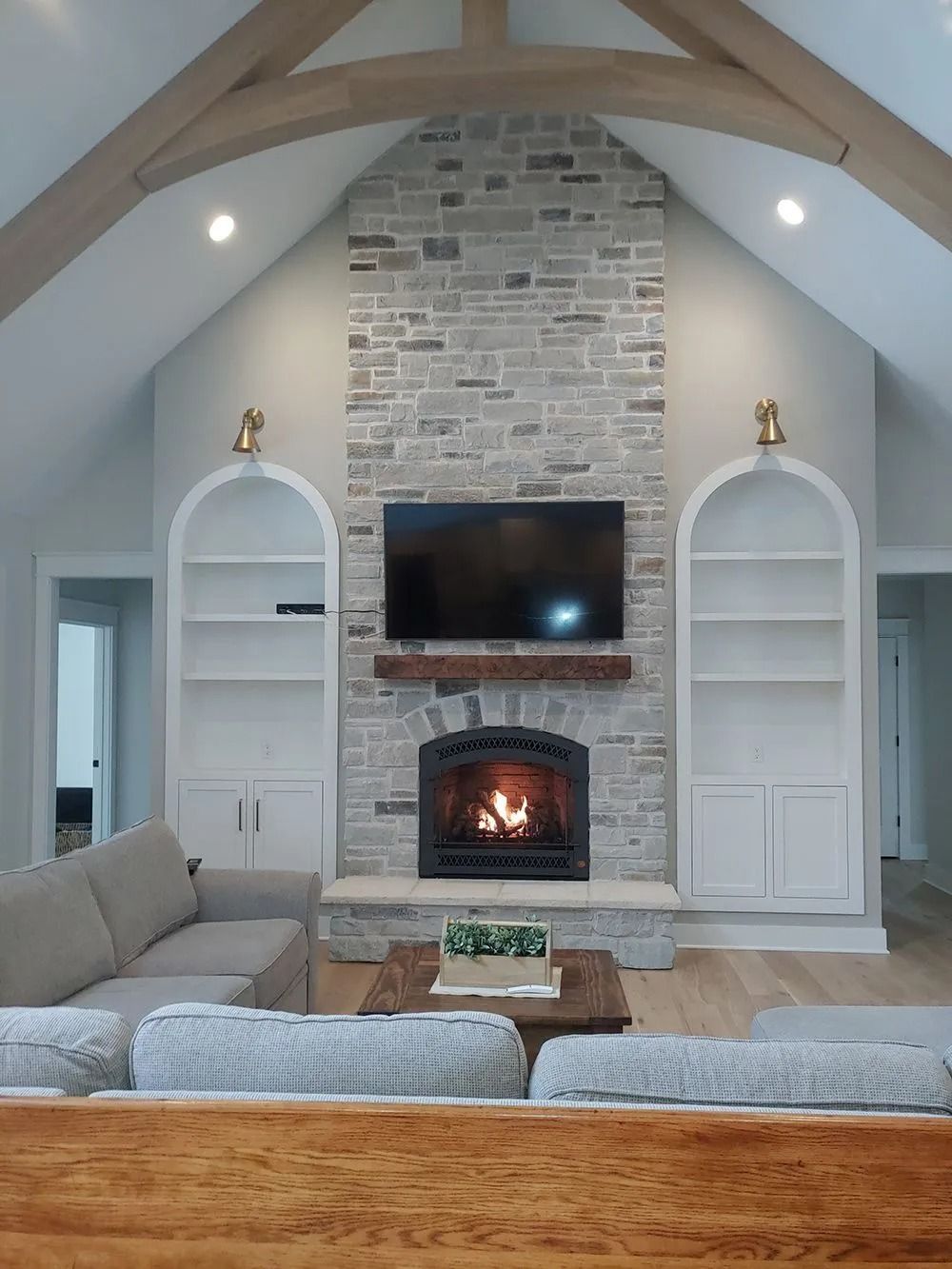Living room with gray brick fireplace, built-in white bookshelves, and a sofa.