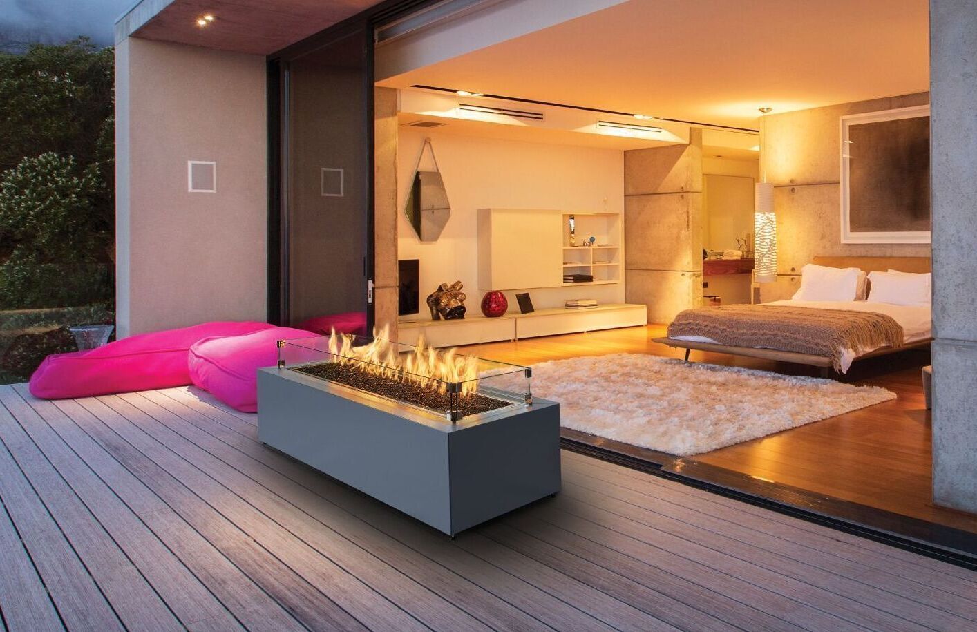 Outdoor patio with modern fireplace, leading to an open bedroom. Pink bean bag chairs on deck.