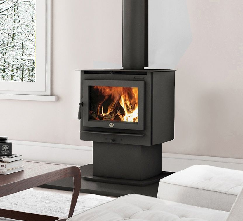 Black wood-burning stove with flames, in a living room near a window with a snowy view.