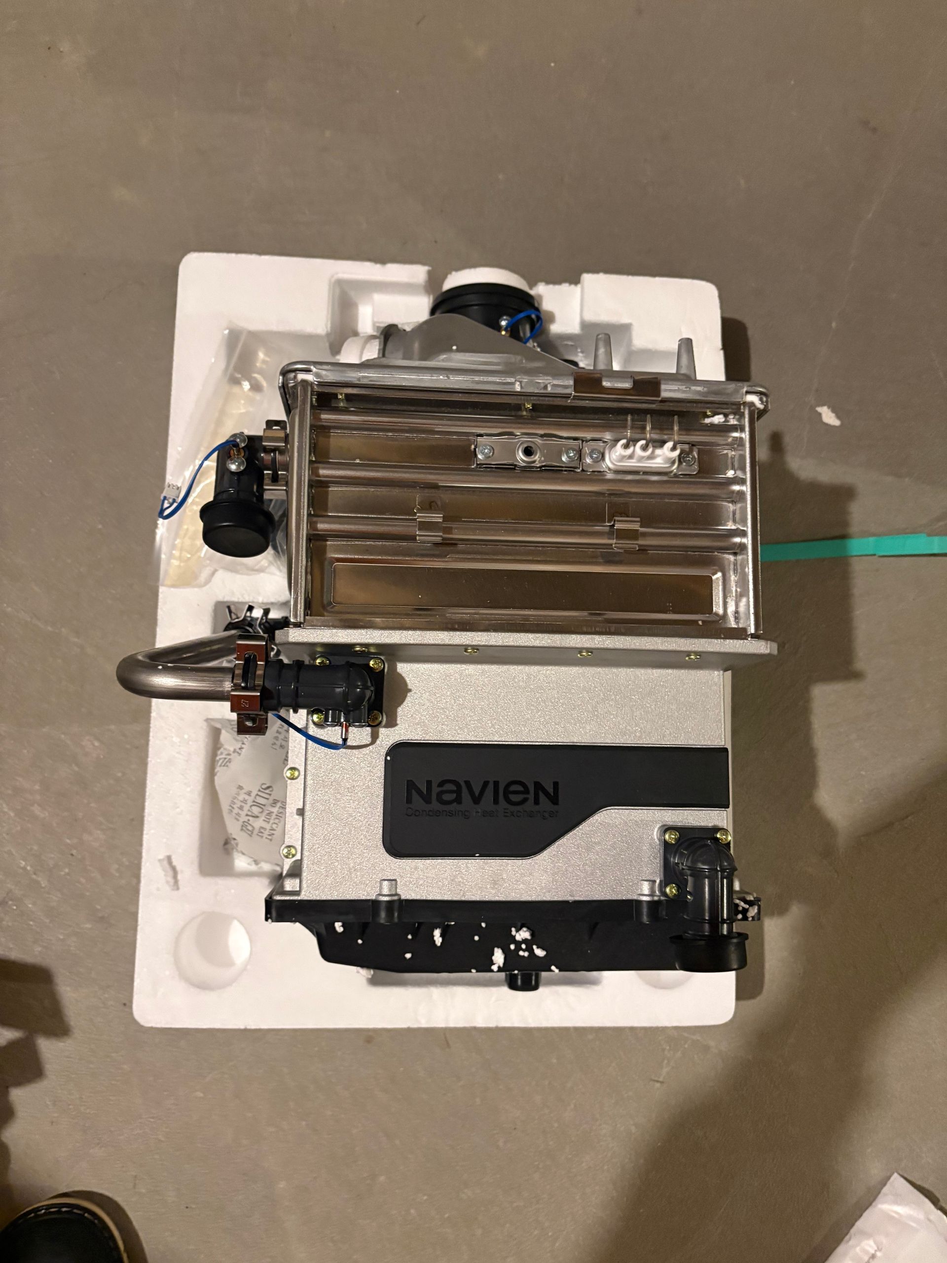 A Navien tankless water heater in protective foam packaging, ready for installation.