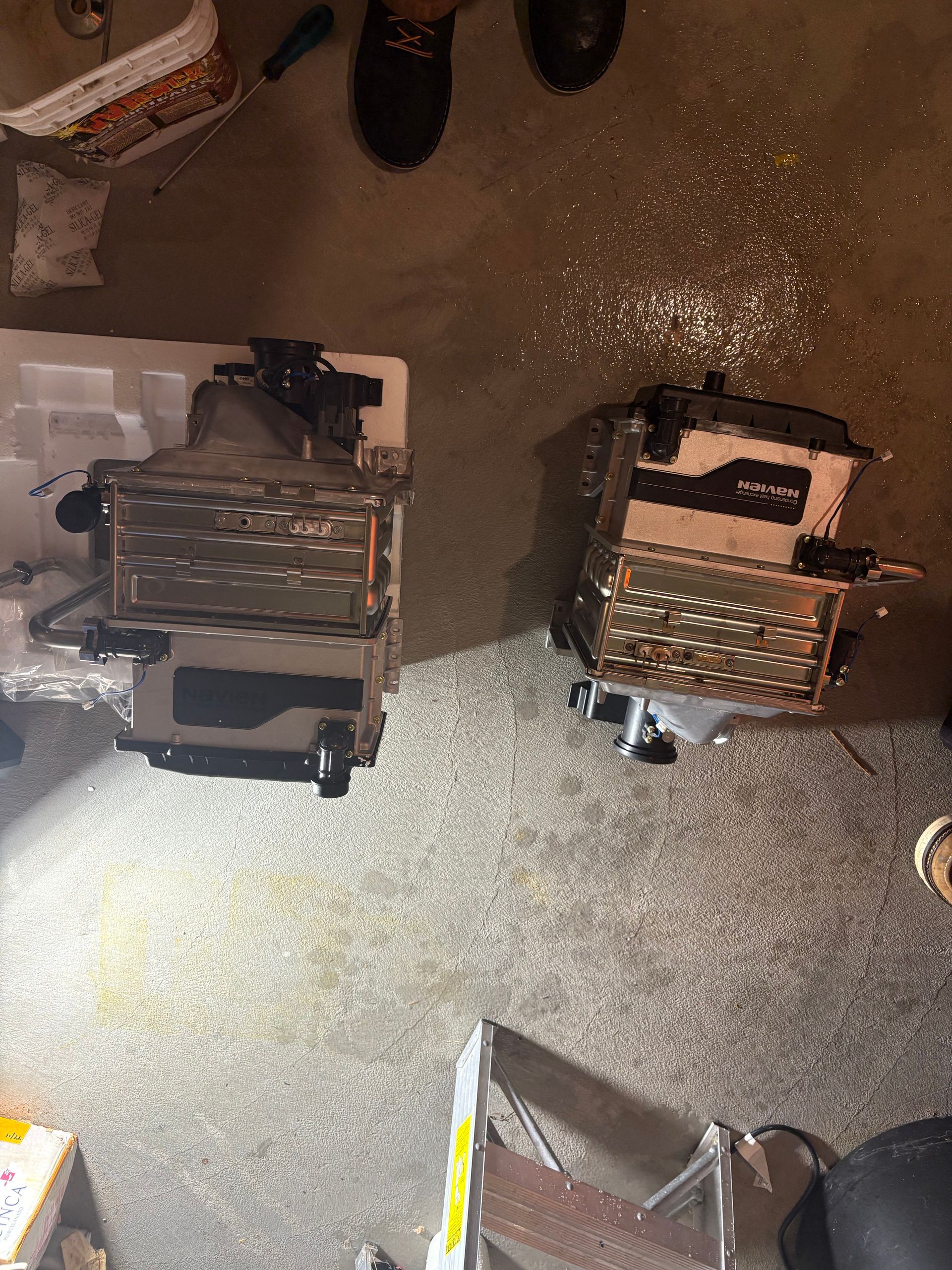 Two open electronic components on a concrete floor with scattered debris.