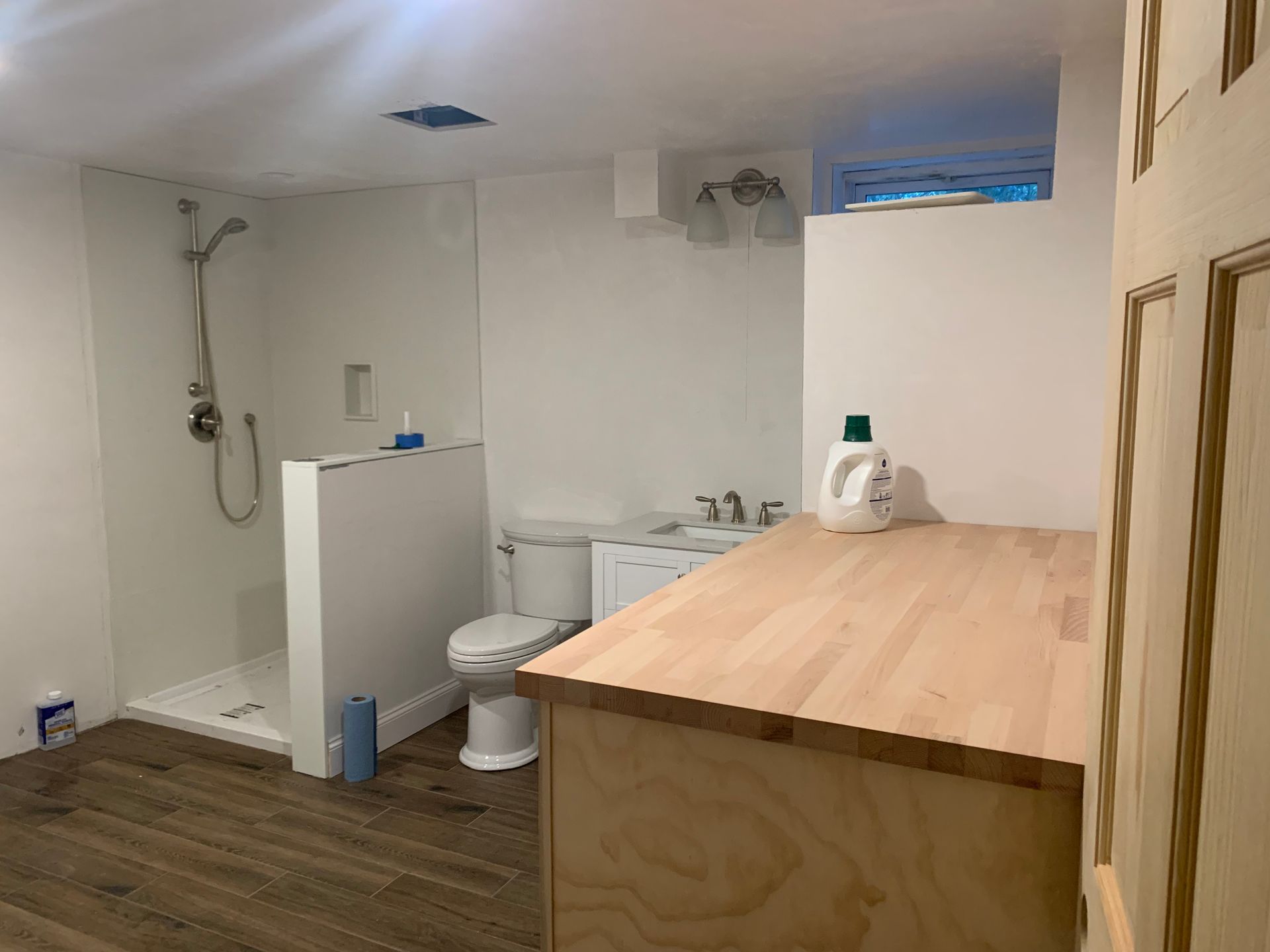 Bathroom with shower stall, toilet, sink, and wooden counter.