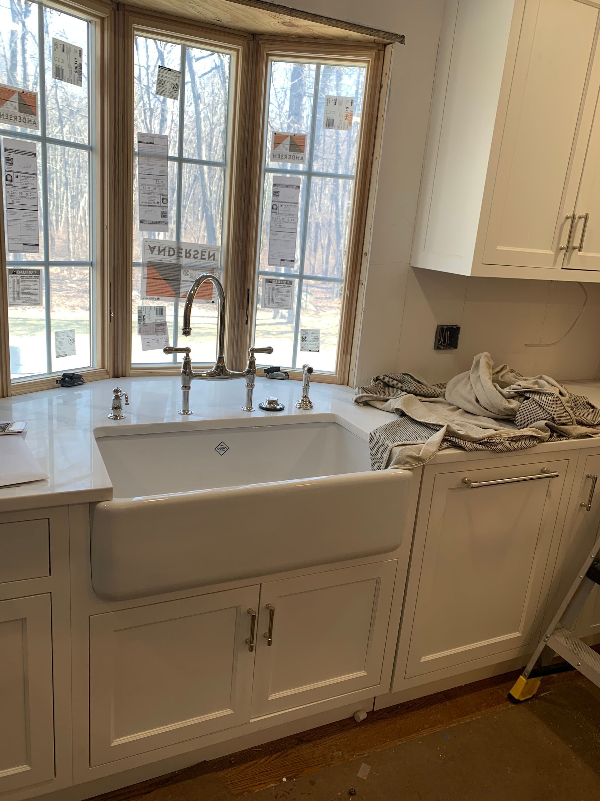 White farmhouse sink in a kitchen with a bay window, under construction.