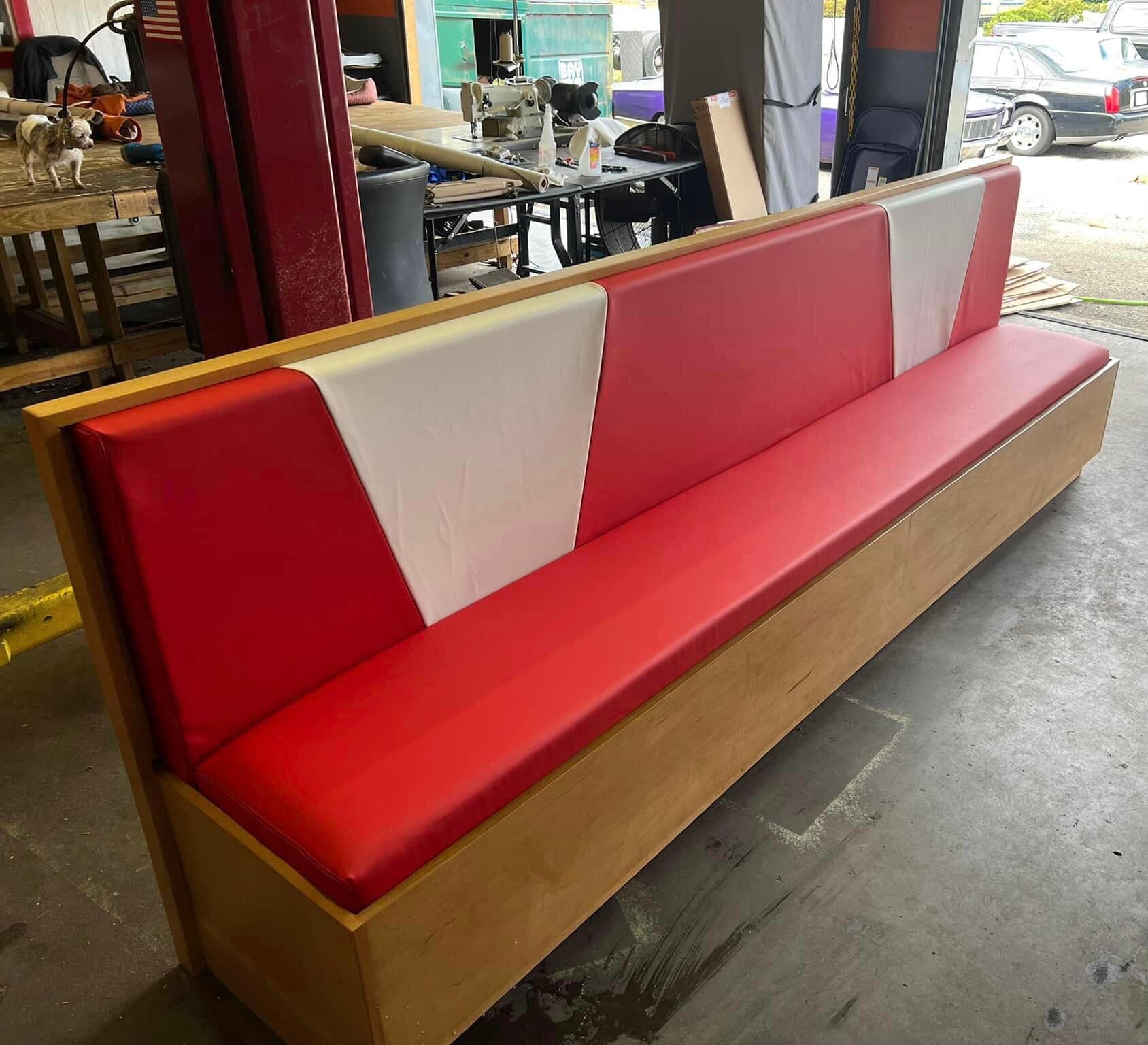 Red and white upholstered booth with a wooden base.