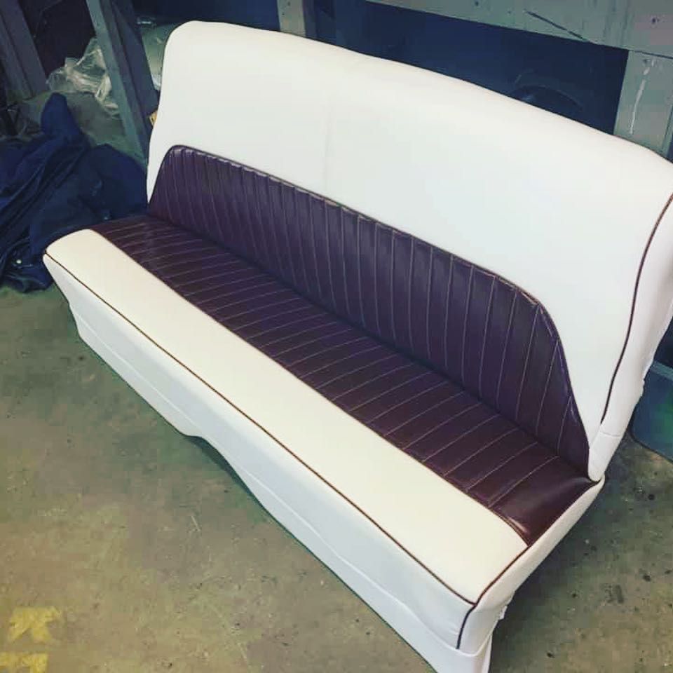 White and brown upholstered bench with vertical stitching.