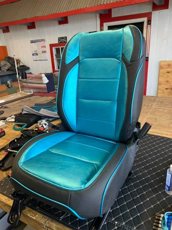 Custom car seat with teal and black leather in a workshop.