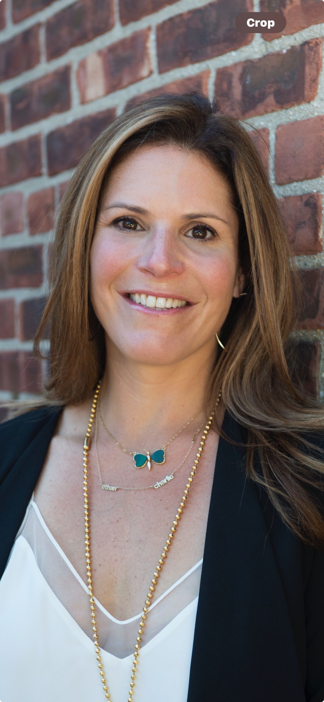 Woman in downward-facing dog yoga pose on a mat, outdoors, framed by green leaves.
