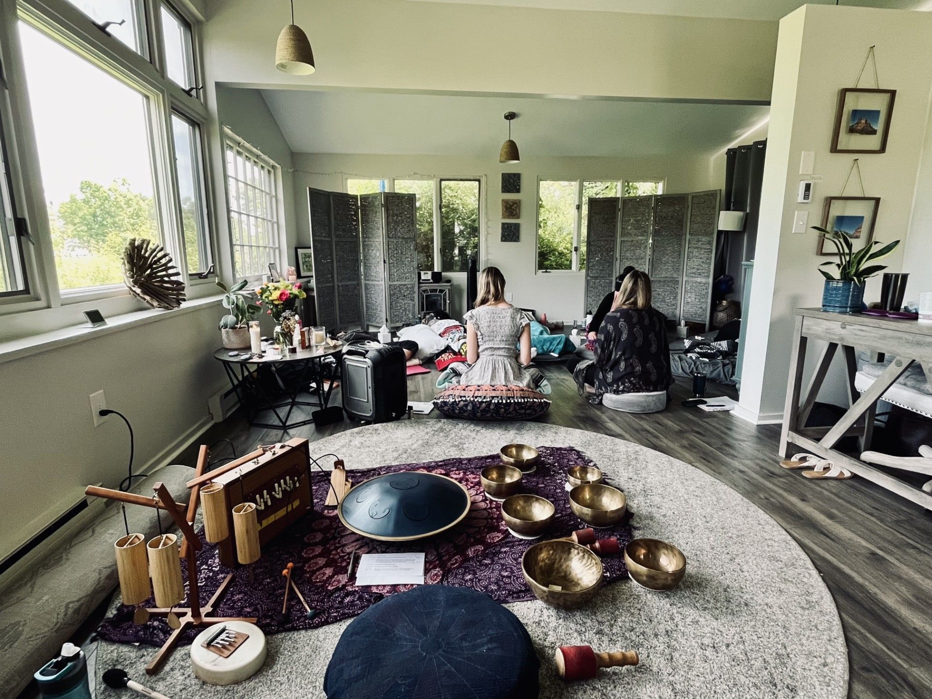 Woman meditating indoors with hands in prayer position, eyes closed. Neutral setting, light-colored clothing.