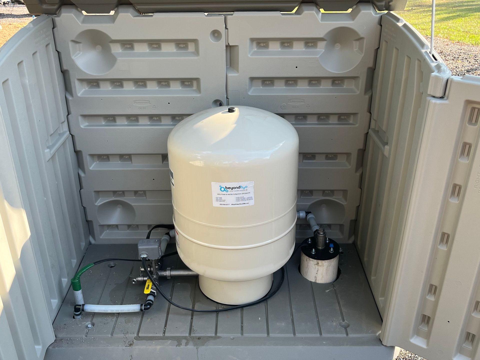 A water tank is sitting inside of a plastic shed.