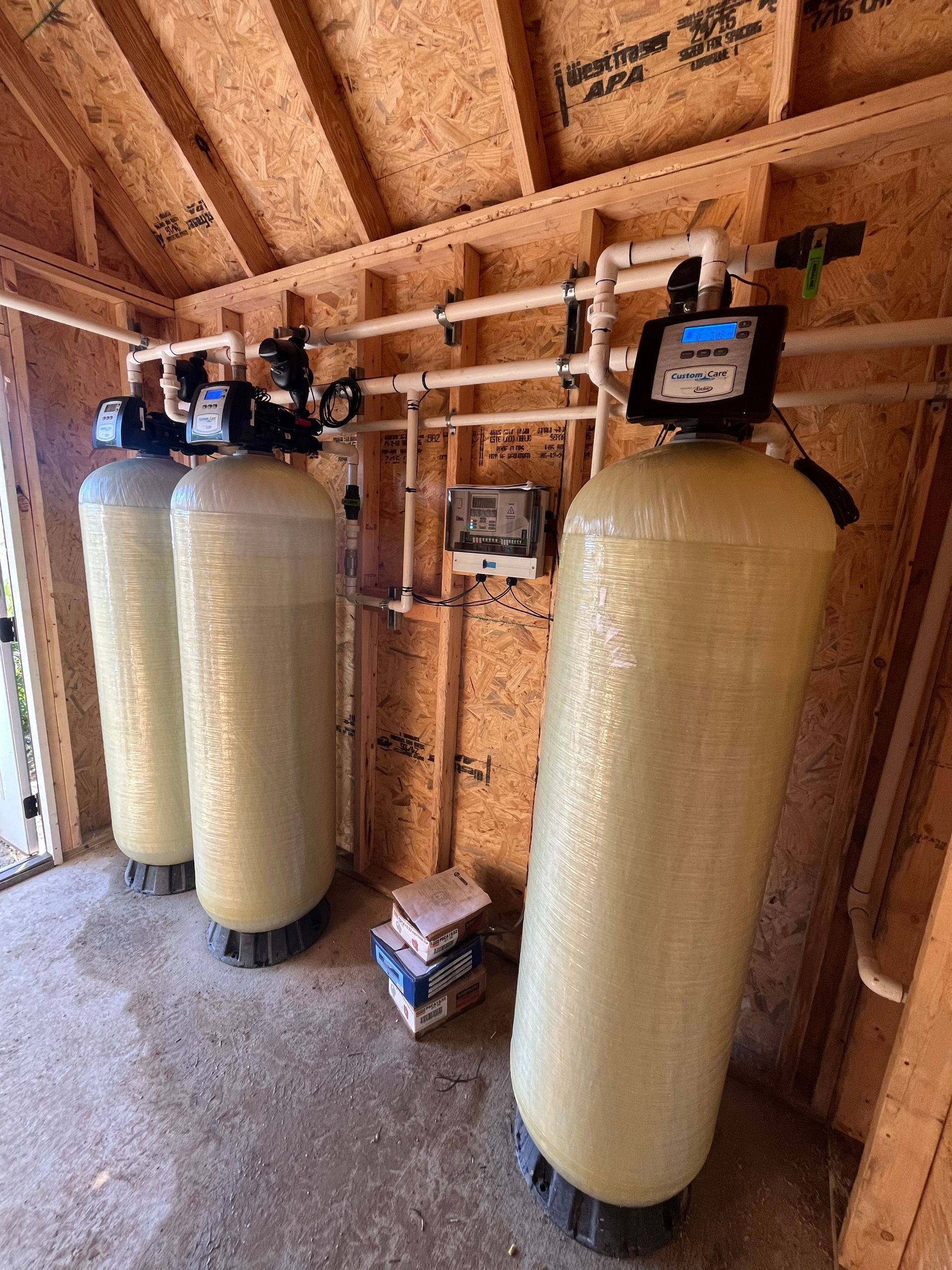Three water tanks are sitting next to each other in a room.