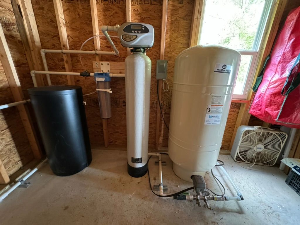 A water softener is sitting next to a water tank in a room.