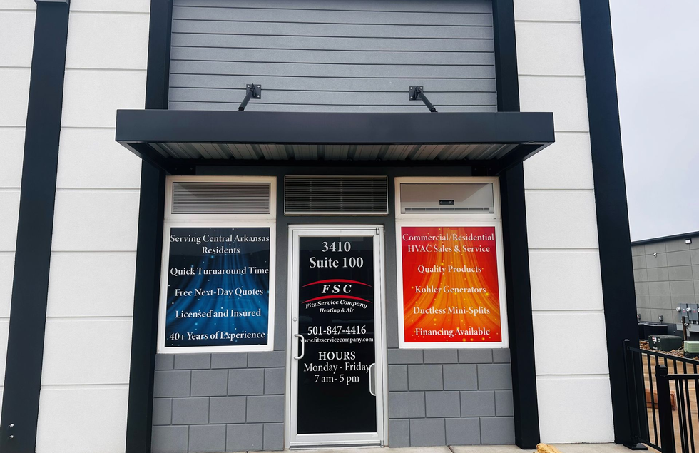 Exterior of a commercial building with a black awning and multiple signs advertising services.