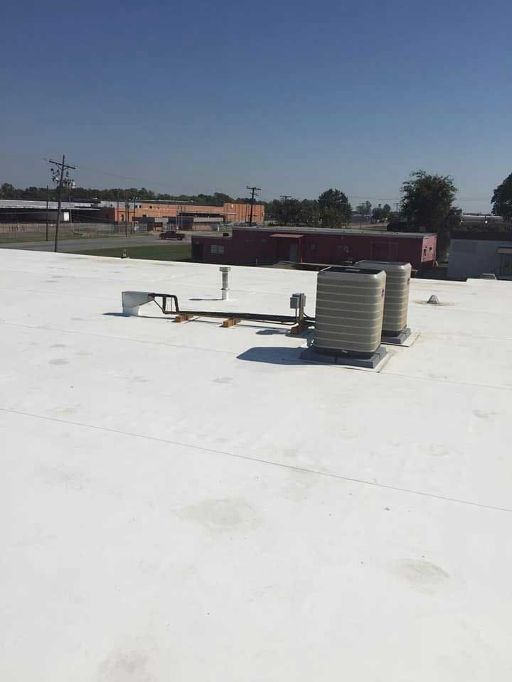 White commercial roof with HVAC units on a sunny day.