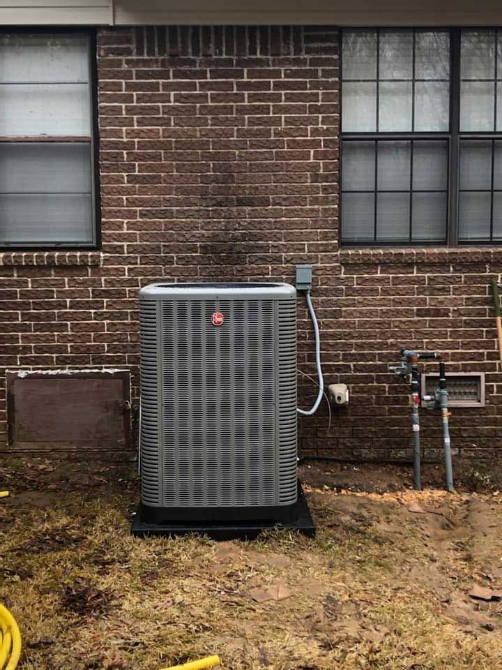 AC unit against a brick wall, with two windows above.