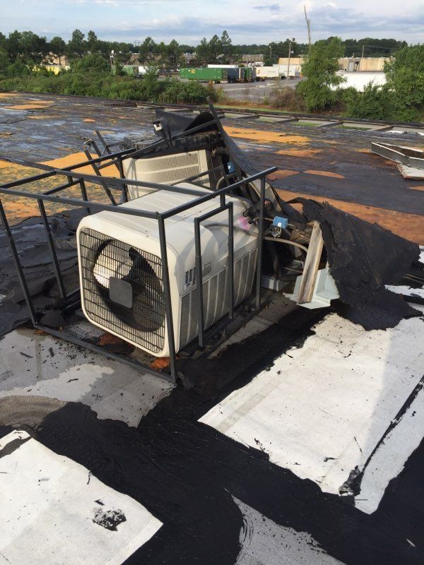 Rooftop view: Damaged HVAC unit, black tarp, metal frame, dark roof.