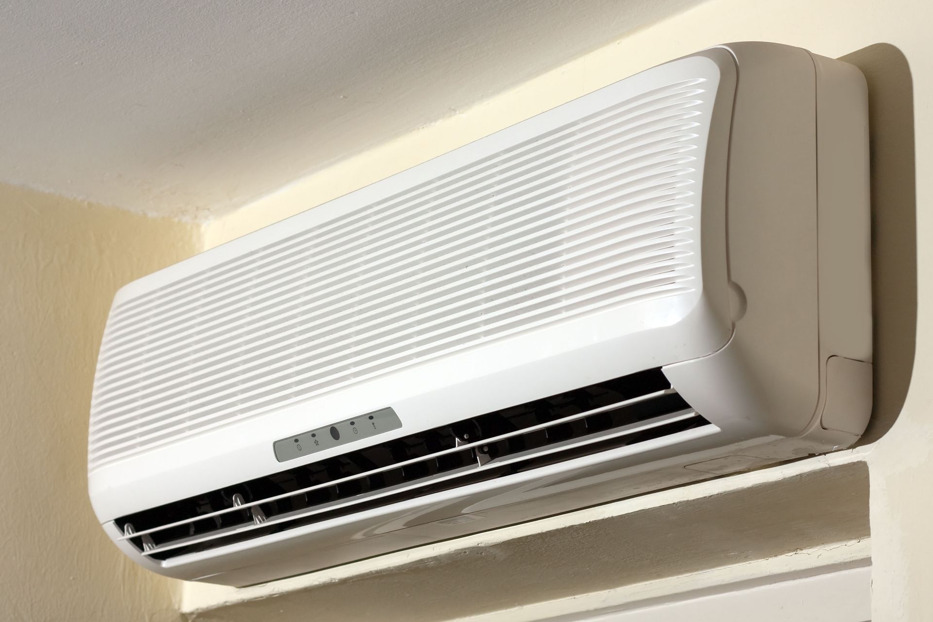 White wall-mounted air conditioner on a pale yellow wall.
