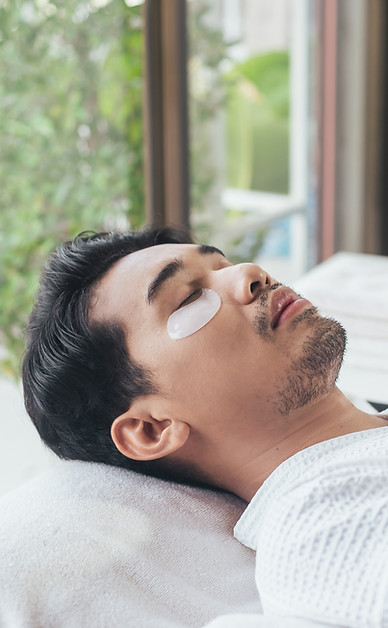 A man is laying on a bed with eye patches on his eyes.