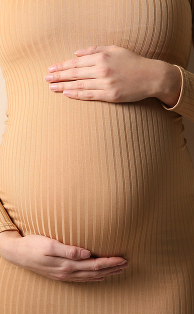 A pregnant woman is holding her belly with her hands.