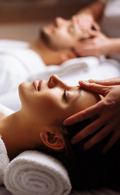 A man and a woman are getting a head massage at a spa.