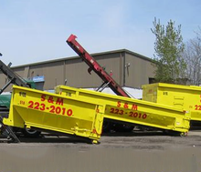 A couple of yellow dumpsters are parked in front of a building.