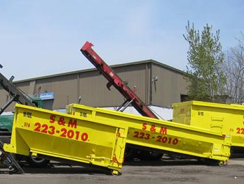 A couple of yellow dumpsters are parked in front of a building.