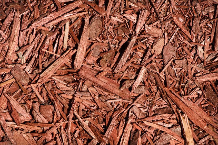 A pile of brown mulch is sitting on the ground.