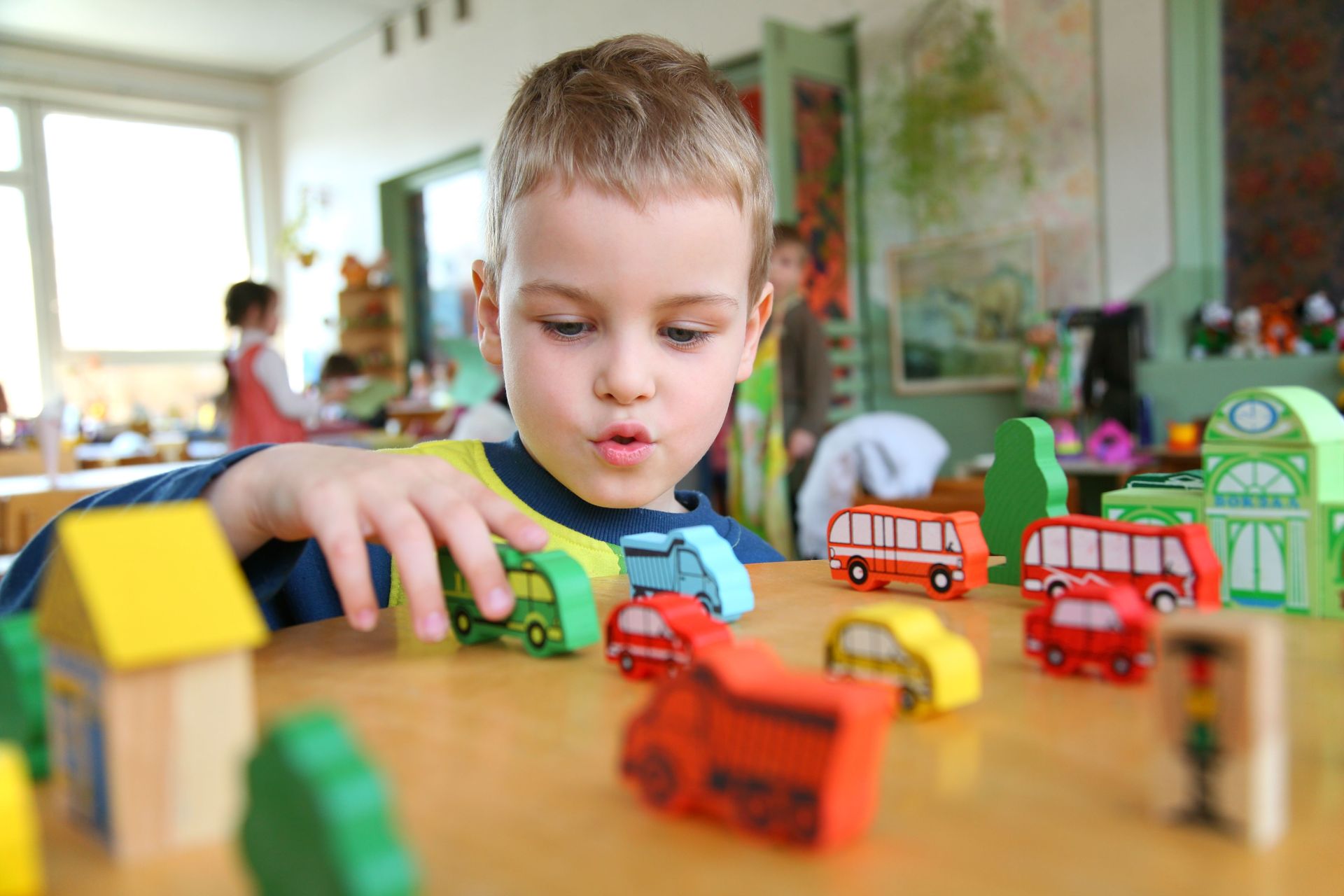Child playing with toy cars on a table in a bright room