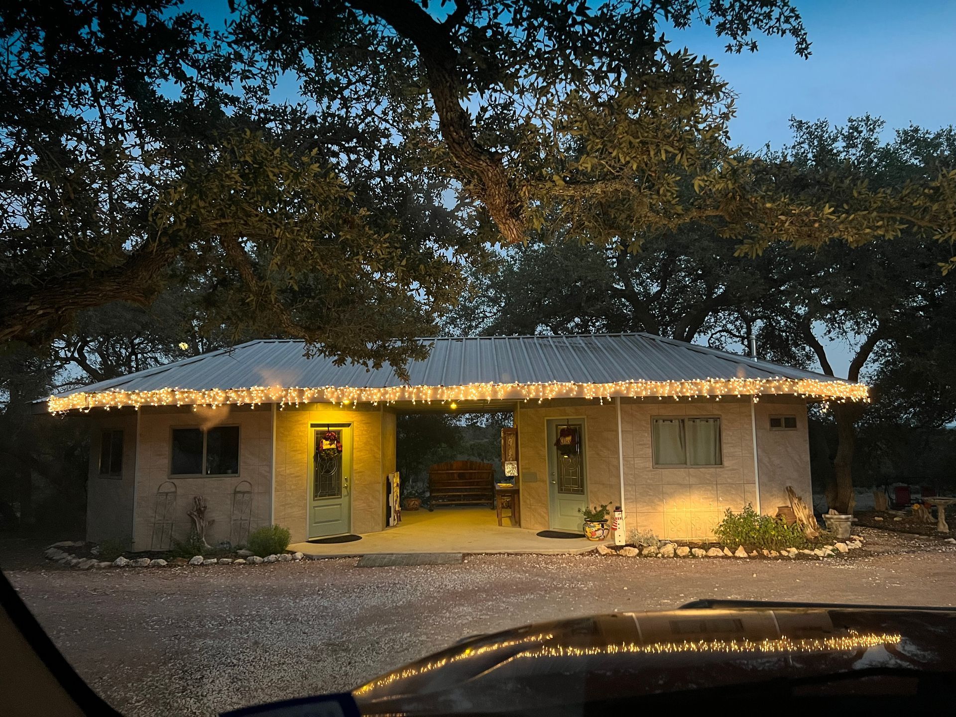 A car is parked in front of a house with Christmas lights on the roof.