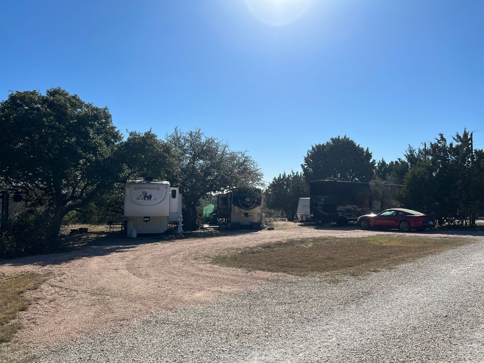 A row of RVs are parked in a gravel lot.