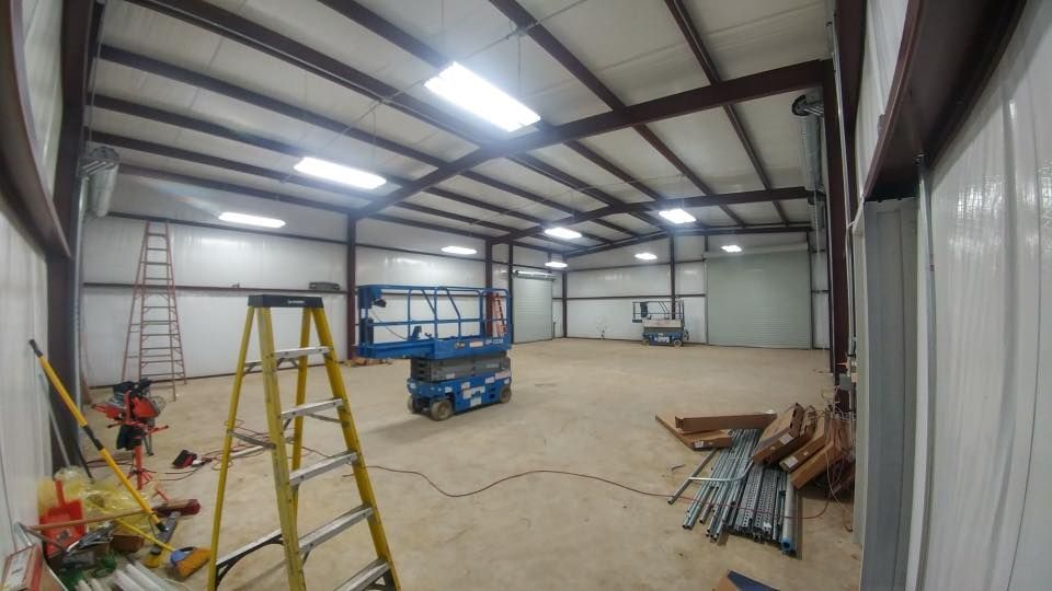 Interior of a large metal building under construction, with ladders, lifts, and equipment.