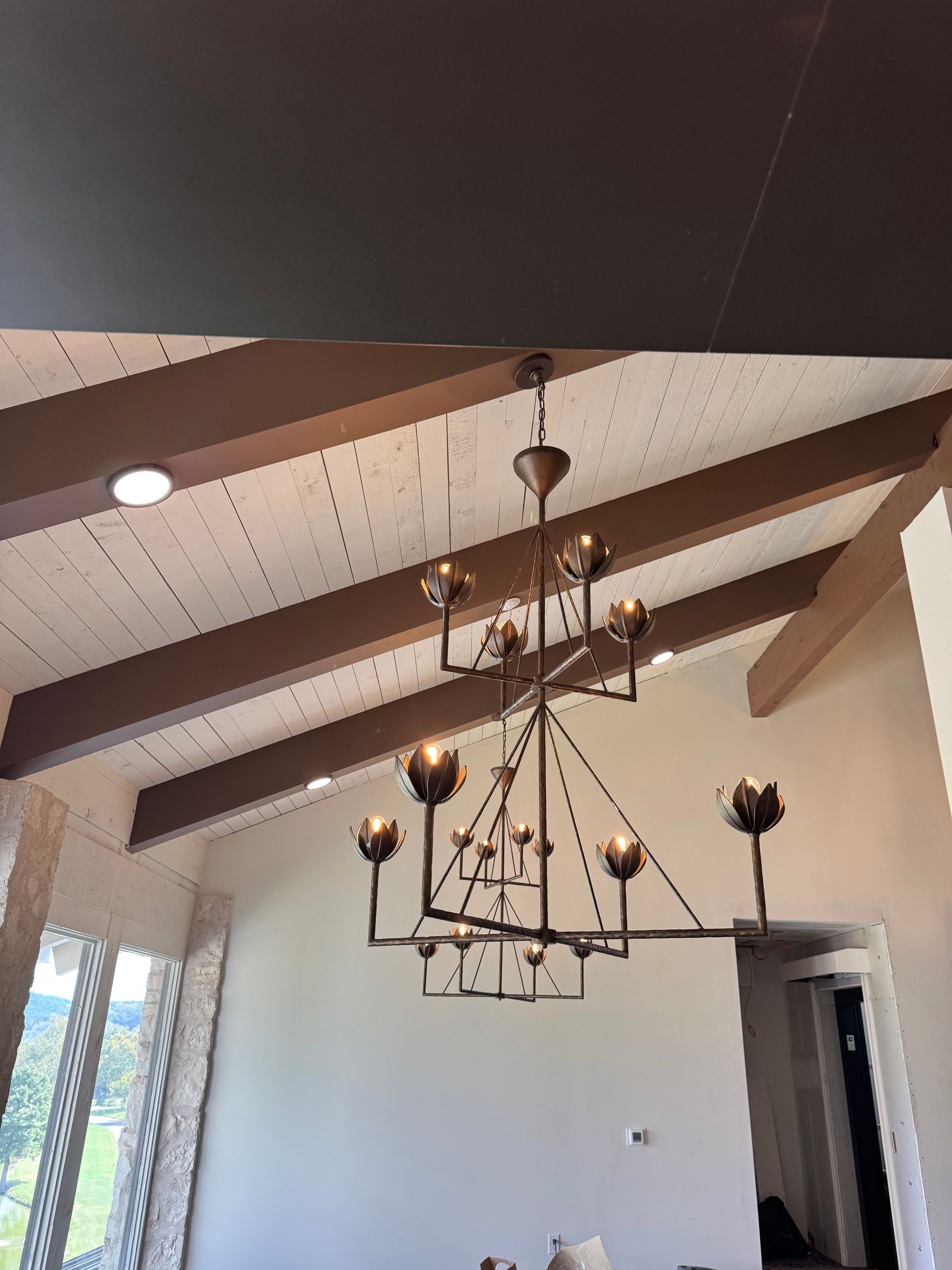 A large chandelier hangs from a brown-beamed ceiling.