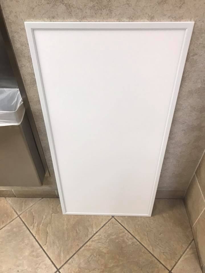 White, trapezoid-shaped ceiling panel in a tiled restroom. A trash can is visible to the left.