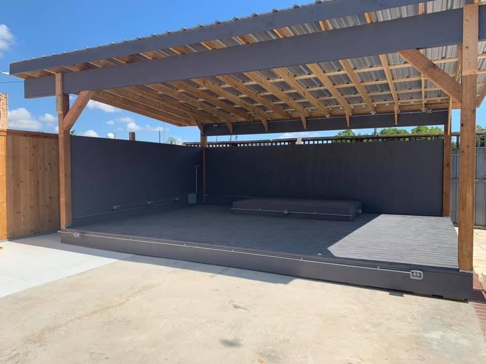 Wooden pergola with a dark gray backdrop and concrete patio.