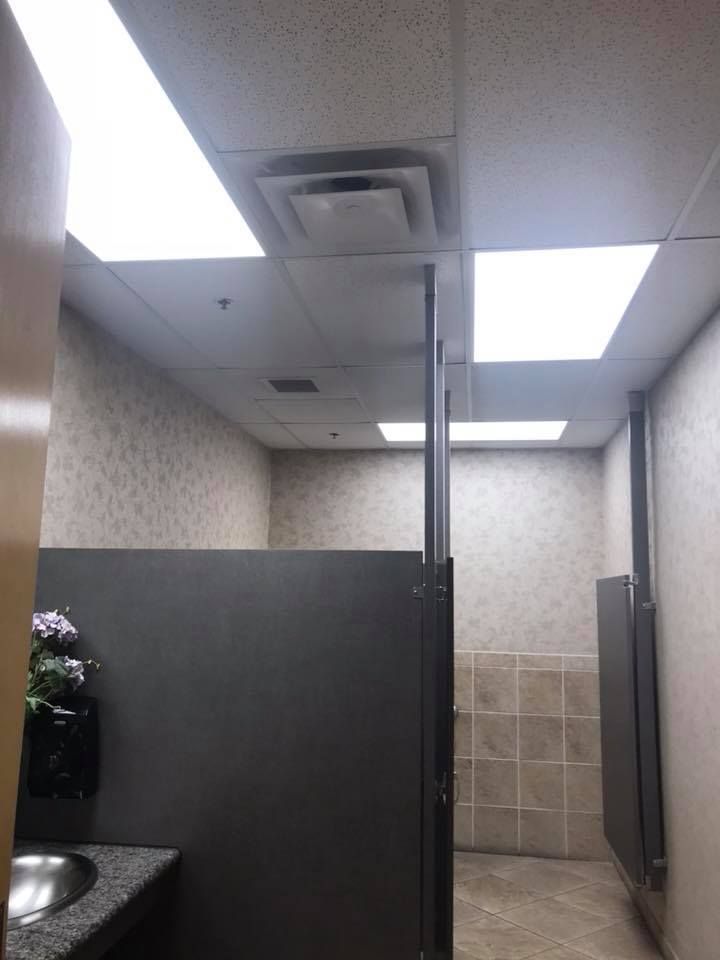 Public restroom with stalls, a sink, and square ceiling lights.