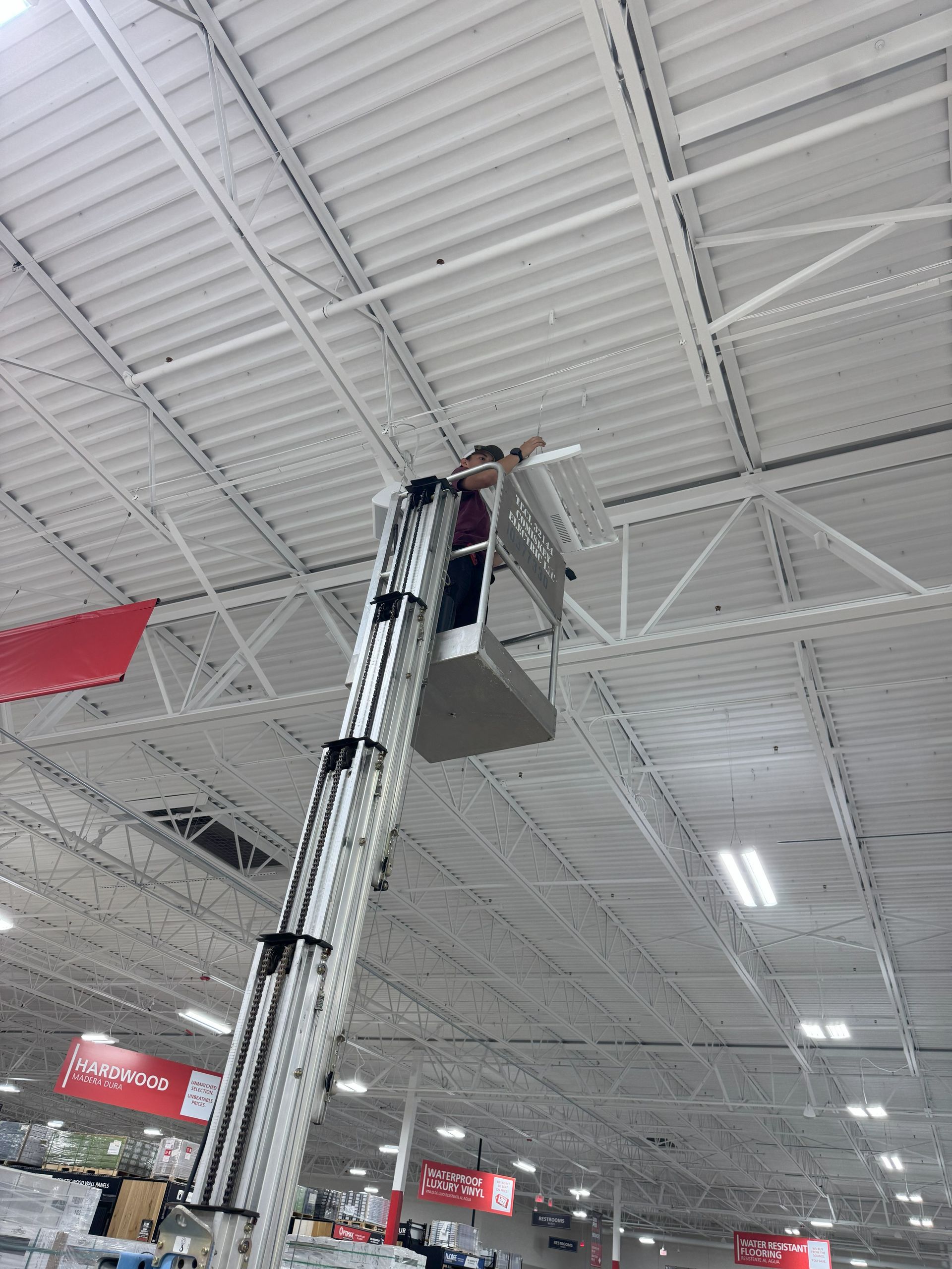 Person in a lift working on the ceiling of a large retail store.