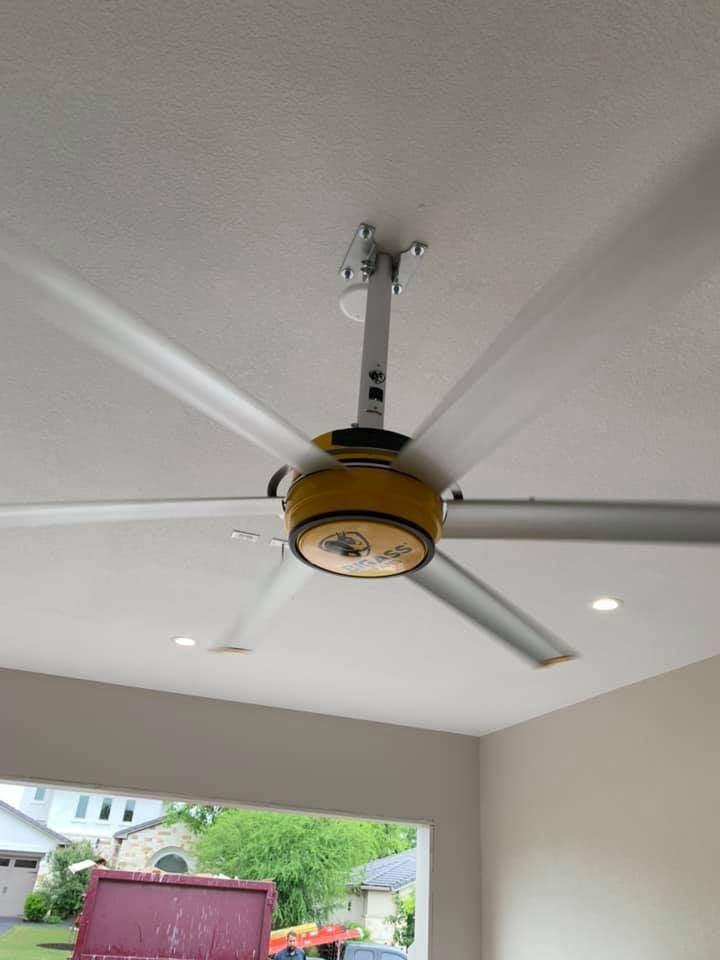 Ceiling fan with yellow accents and long silver blades, mounted on a white ceiling.